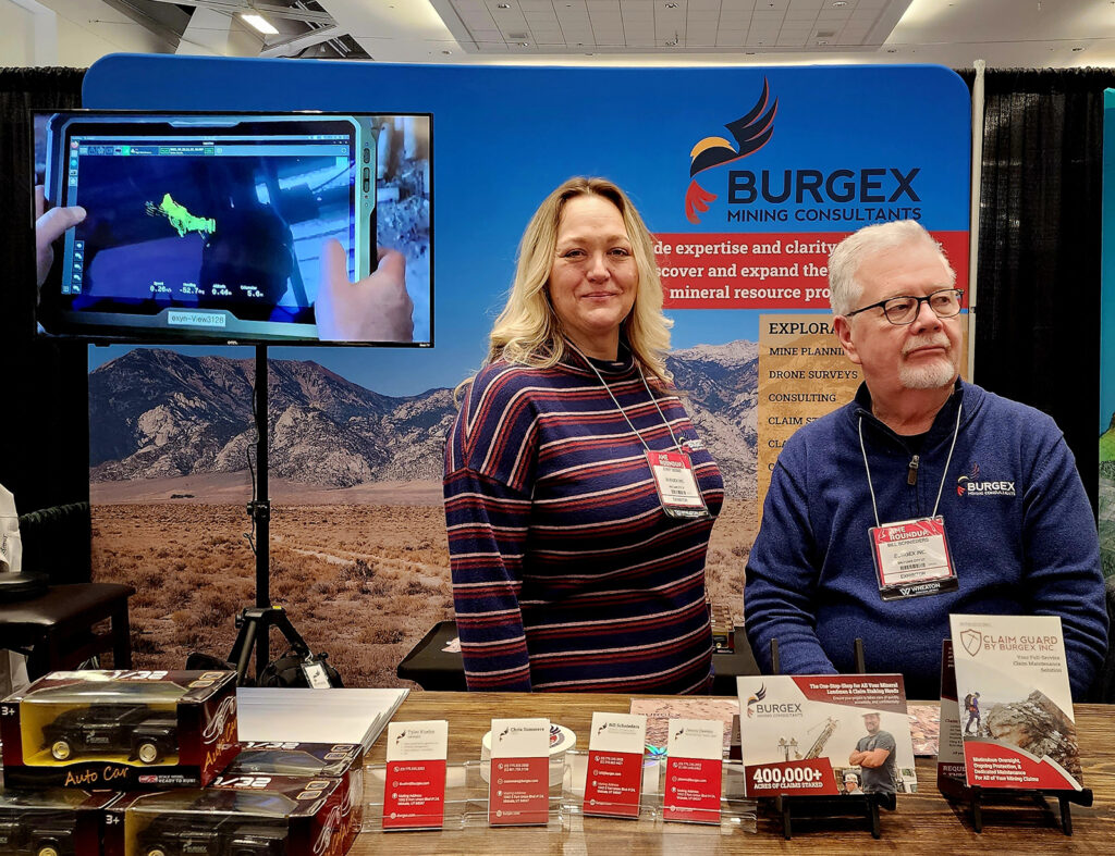 Jenny Deems and Bill Schnieders smile at passerby's at the Burgex Mining Consulting booth at AME Roundup 2023.
