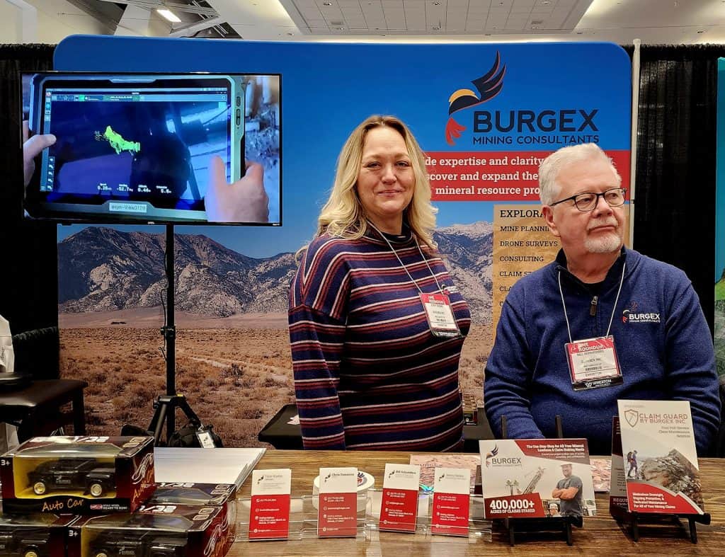 Jenny Deems and Bill Schnieders smile at passerby's at the Burgex Mining Consulting booth at AME Roundup 2023.